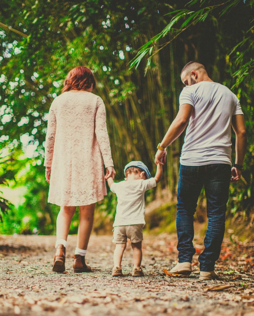 Family with young daughter walk bamboo path in village