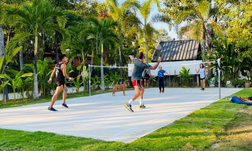Mixed group play badminton with dog watching