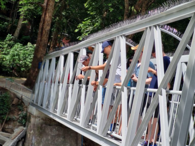 Addiction recovery group feed the fish from iron bridge in Thailand national park