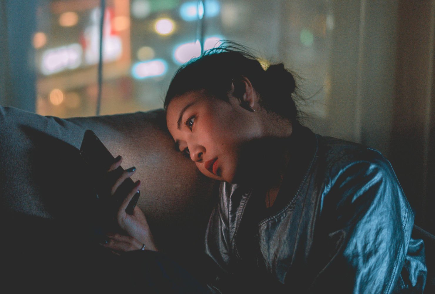 Tired iphone woman Woman stares at phone in lonely appartment