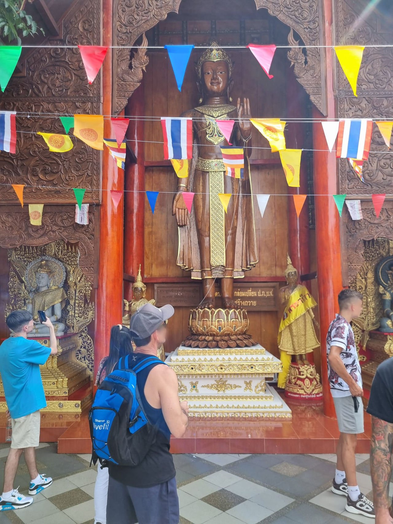 Bunting surrounds wooden Buddha statue at temple complex