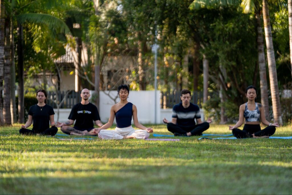 A group of five people practising meditation at the One Step Rehab facility.