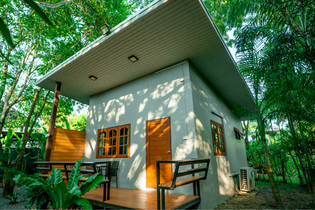 Small private cabin in rehab centre surrounded by lush tropical greenery with a wooden deck and outdoor seating area.