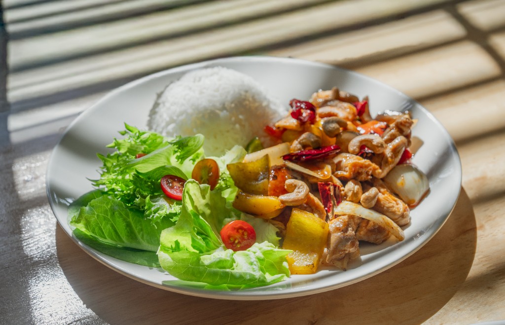 Thai chicken stir-fry with cashews, rice, and fresh salad served at One Step Rehab